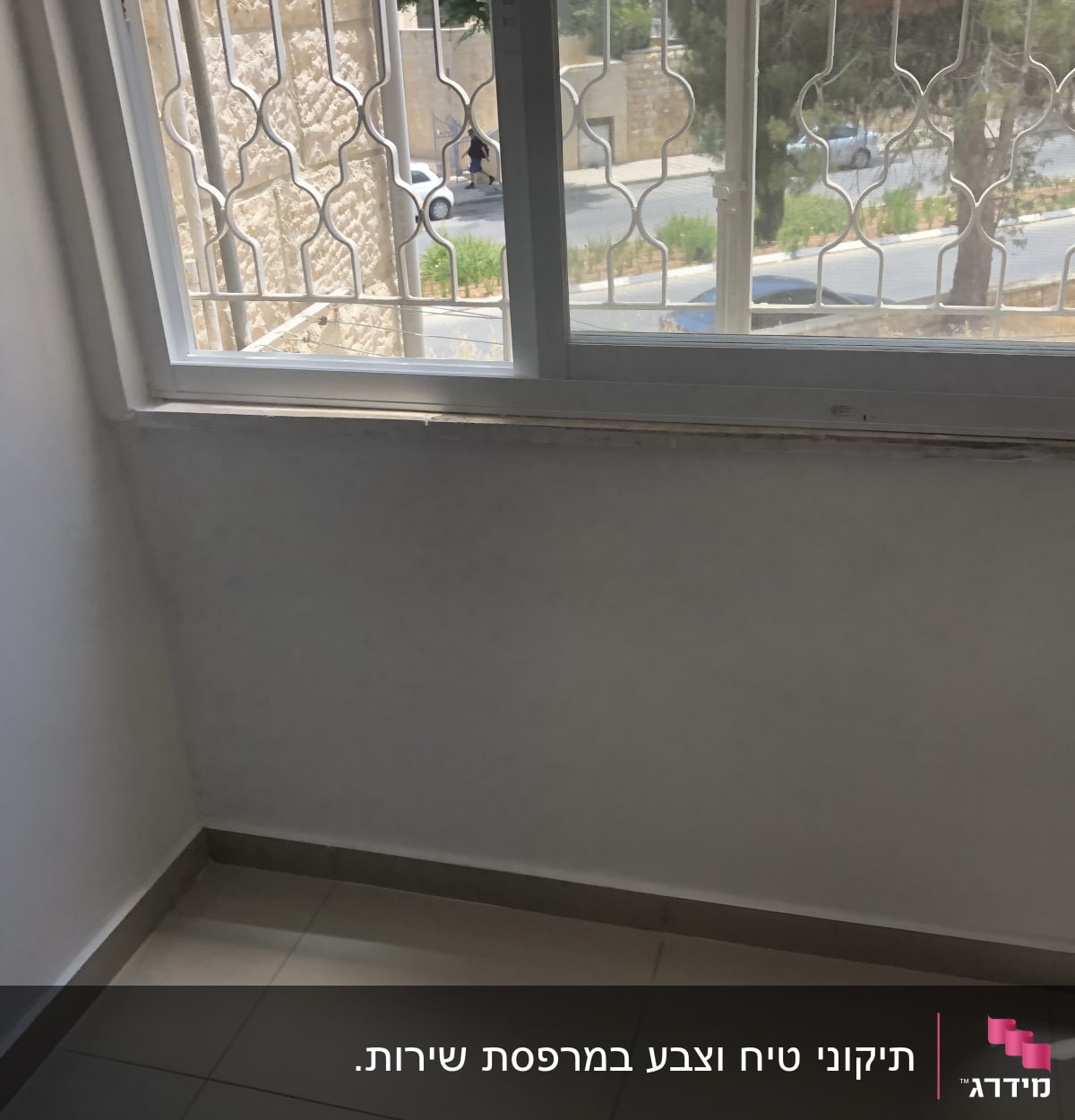 קיר צבוע לבן ליד חלון עם סורגי מתכת